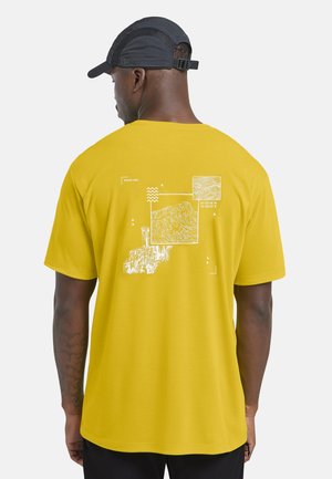 Gelbes T-Shirt mit kurzen Ärmeln, das auf der Rückseite weiße Grafiken zeigt, darunter Karten und Koordinaten, mit einem lässigen Schnitt.