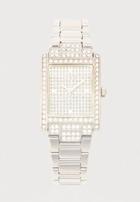 Sudraba taisnstūra pulkstenis ar kristāliem rotātu rāmīti, strukturētu ciparnīcu un metāla saišu aproci. Zīmola logotips redzams pulksteņa centrā.