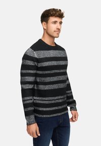 Sort og gråstribet sweater med en struktureret overflade, der har runde halsudskæring og lange ærmer. Materialet synes at være strikket.