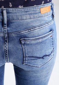 Jeans de mezclilla en azul claro con un acabado deslavado, que cuentan con dos bolsillos traseros, costuras visibles y una etiqueta de cuero en la cintura.