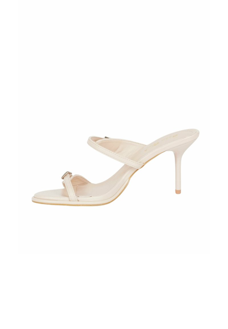 Sandali con tacco alto in un morbido beige, caratterizzati da due cinghie e una piccola fibbia metallica. Presentano una finitura liscia e un design a punta.