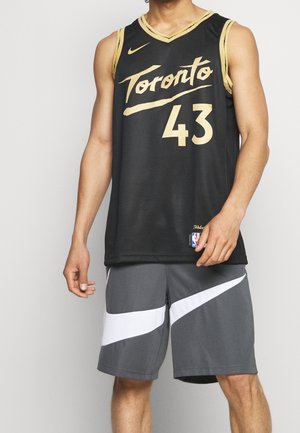 Mężczyzna ubrany w czarny koszulkę koszykarską Toronto z numerem 43 oraz szare spodenki Nike z białym logo Swoosh.