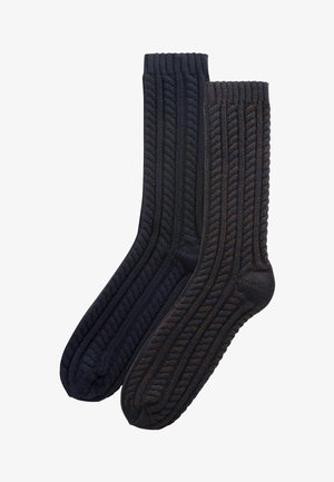 Dark knitted socks featuring a cable pattern. Ribbed cuffs and varying shades of dark blue and brown. Soft texture and classic design.