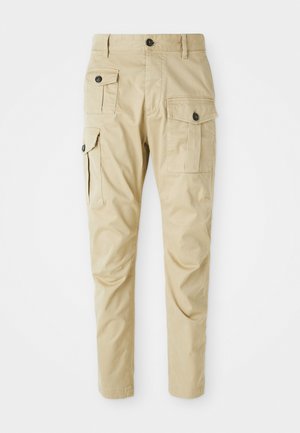 Pantalones cargo beige con un diseño ajustado, que cuentan con dos bolsillos laterales y un cierre de botón, hechos de una tela suave con un sutil brillo.