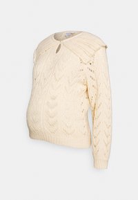 Stickad gräddfärgad graviditetskofta med öppet mönster, rundad krage och ett nyckelhål i halsringningen. Långa ärmar med ribbade muddar.