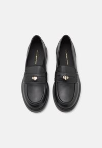 Mocassins en cuir noir à texture lisse, bout arrondi et accents métalliques décoratifs sur les bandes. Dotés d'une semelle intérieure de marque.