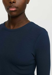 Marineblauwe geribbelde long-sleeve top met een ronde halslijn, voorzien van een textuurstof en duidelijke naden langs de schouder.