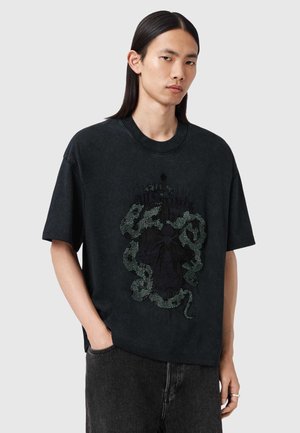 Schwarzes, übergroßes Baumwoll-T-Shirt mit einem strukturierten grafischen Design aus Schlangen und Blumen in verschiedenen Dunkelgrüntönen und Schwarz.