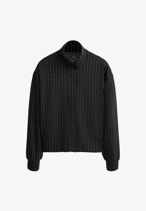 Fekete cipzáras dzseki fehér rácsmintával, magas gallérral, hosszú ujjakkal és oldalzsebekkel.