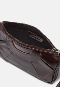 Borsa in pelle marrone con chiusura a zip, dotata di una fodera interna nera, logo impresso e dettagli di cucitura rossa discreti.