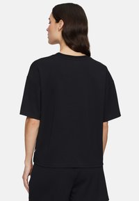 Zwart katoenen T-shirt met een relaxed fit, korte mouwen, ronde hals en een effen achterkant. Bevat een klein logodetail bij de zoom.