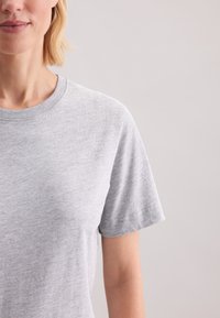 Lysegrå t-shirt med korte ærmer, lavet af en blød bomuldsblanding, med en klassisk rund halsudskæring og en glat overflade uden mønstre.