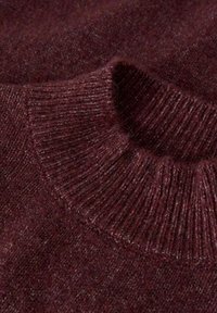 Bordowy sweter dziergany z prążkowanym kołnierzem, miękką fakturą i nieco zróżnicowanym wzorem dzianiny. Skupia się na bogatej kolorystyce i przytulnym designie.