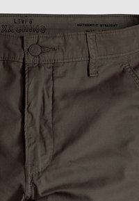 Pantalon droit authentique Levi’s XX Chino marron montrant les détails du bouton, de la boucle de ceinture et de la poche.