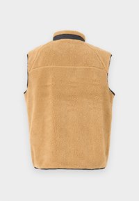 Fleece vest in warm beige met een gestructureerde buitenkant, zwarte afwerking langs de armsgaten en kraag, en een eenvoudige achterkant zonder versieringen.