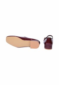 Scarpe slingback in pelle verniciata color bordeaux con punta rotonda, tacco basso a blocco e una fascia minimale. Texture liscia e colore solido.