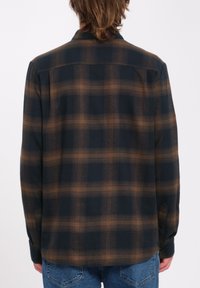 Long-sleeve plaid shirt in navy and brown, featuring a relaxed fit, button cuffs, and a rear yoke detail. Made from a soft fabric.