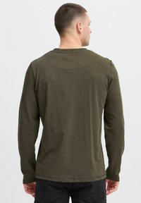Olivenfarbener Langarm-T-Shirt aus weichem Material, mit rundem Ausschnitt und einem schlichten Design ohne Muster oder sichtbare Hardware.
