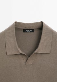 Polo en maille taupe à manches courtes avec col en V ouvert et étiquette Massimo Dutti à l'intérieur du col.