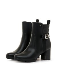 Botas de tobillo de cuero negro con un tacón voluminoso, paneles laterales elásticos, detalle de hebilla plateada y acentos texturizados en los laterales.