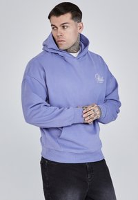 Sudadera morada con un bolsillo delantero y capucha con cordón. Confeccionada con tela suave, presenta un corte relajado y puños acanalados.