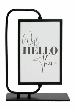 Schwarzer Metallständer, der ein gerahmtes weißes Schild mit dem Text "Well HELLO There" in gemischten Schriftarten hält.