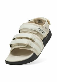 Hvide og beige sandaler med tre justerbare Velcro-remme og polstret sål; tekstureret overdel og kontrasterende sort ydersål.