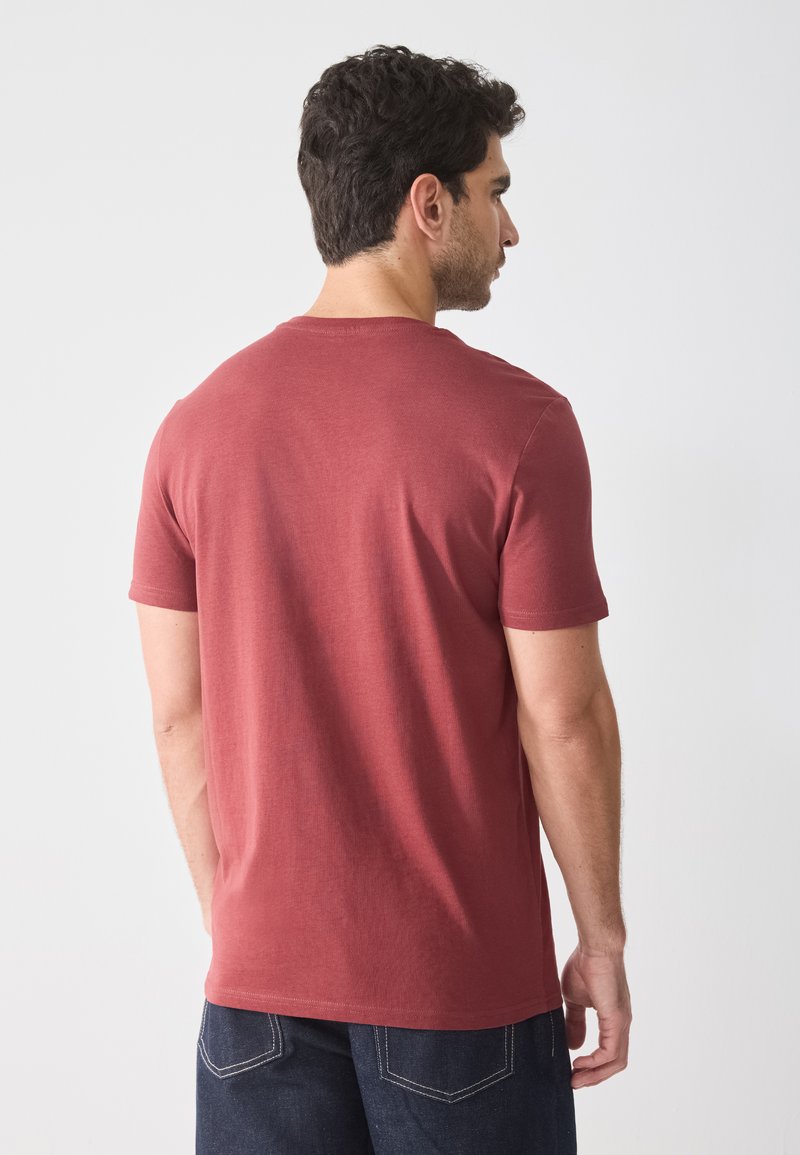 T-shirt en coton rouge avec un col rond et des manches courtes, présentant une texture lisse et un design simple et classique.