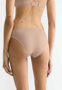 Beige Baumwollunterwäsche mit glatter Textur, mittlerer Bundhöhe und dezentem Logo-Detail am Bund, ohne sichtbare Nähte.