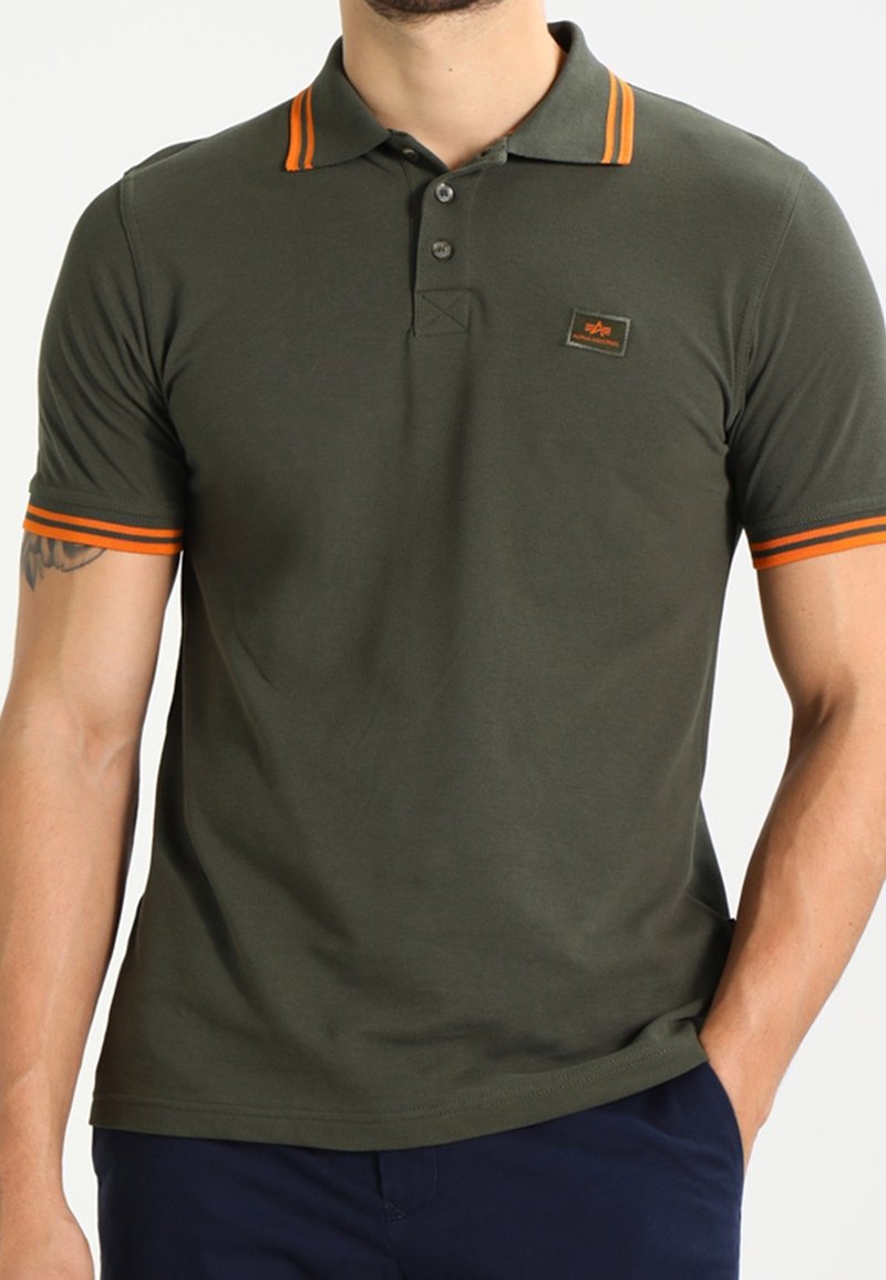 Olivgrön polotröja i bomull med orangea ränder på kragen och ärmarna. Har en frontal logotyp-patch och en klassisk passform.