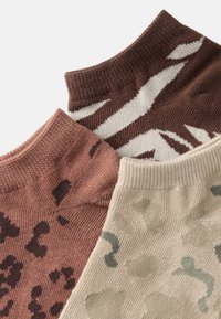 Tre par ankelsokker: en i brun med hvit stripe, en i rustfarge med svarte prikker, og en i beige med grønne abstrakte former.