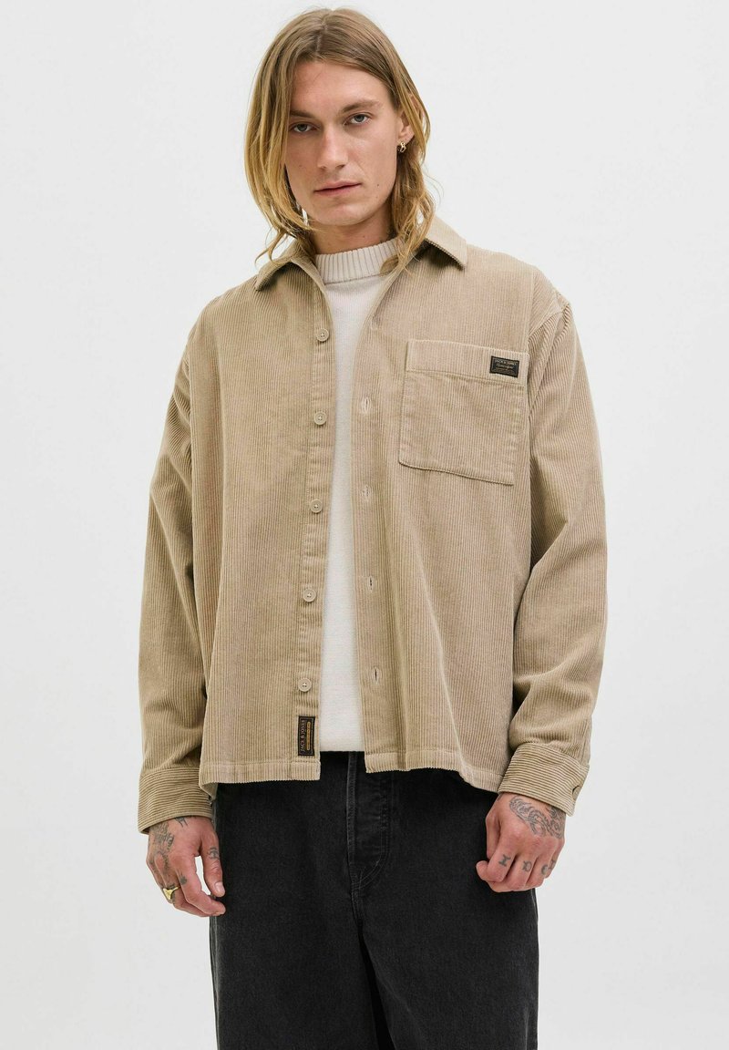 Beige corduroy shirt met een knoopsluiting aan de voorkant, kraag, enkele borstzak en geweven label. Lange mouwen met geknopte manchetten.
