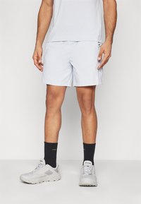 Lyseblå treningsshorts laget av fukttransporterende stoff. Har side lommer, pent kant, og en logo nederst til venstre.