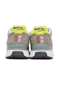 Le sneaker Lotto Legend presentano una tomaia in suede grigio, accenti giallo fluo e una suola intermedia bianca con una suola esterna nera. Testo giapponese sui talloni.
