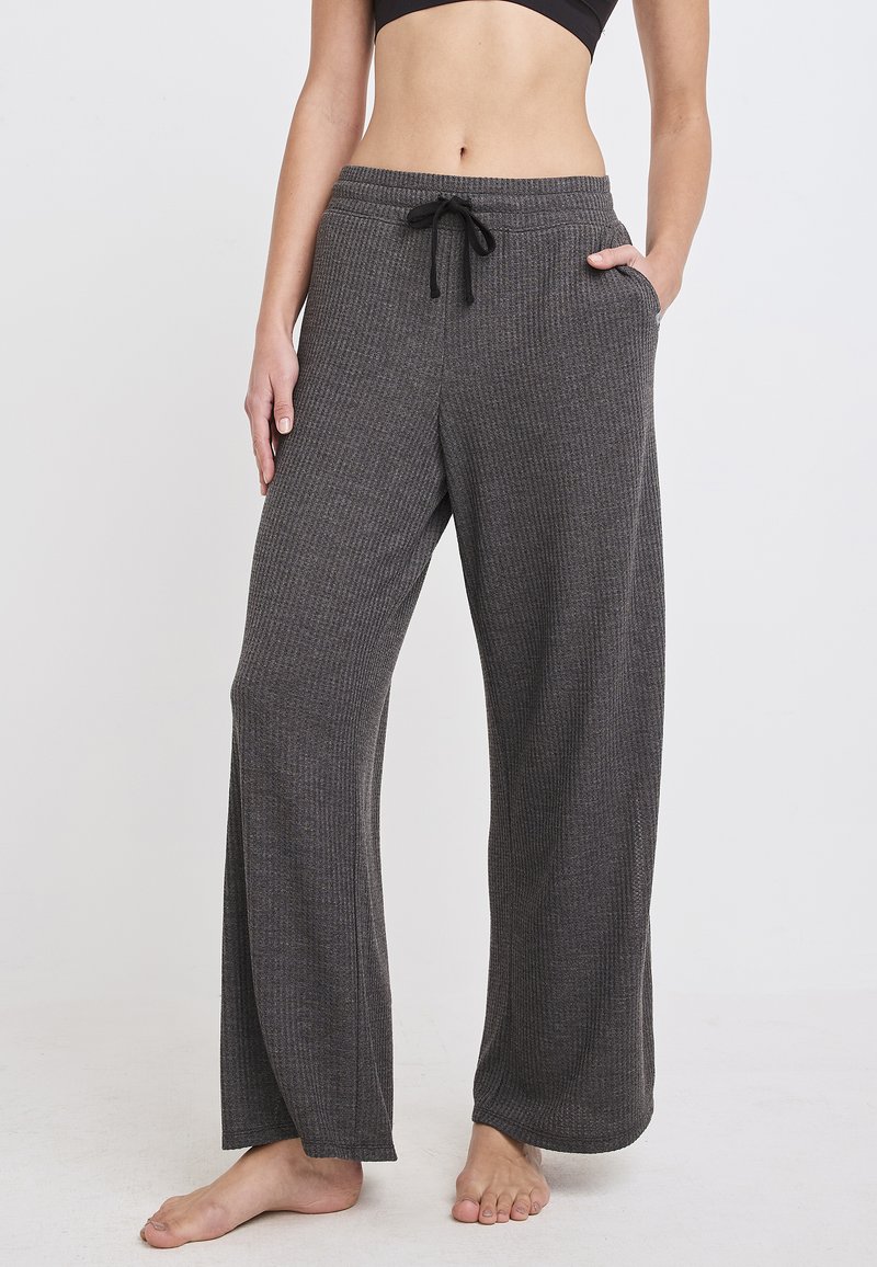 Weite Lounge-Hosen aus geripptem grauen Stoff mit einem elastischen Bund und einem Kordelzug sowie seitlichen Taschen. Weiche Textur.