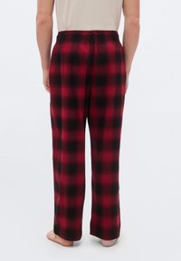 Pantalon de pyjama à carreaux rouges et noirs en tissu doux, avec une taille élastique et une coupe à jambes larges.