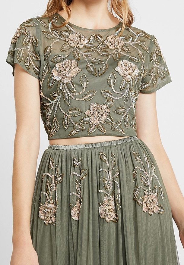 Borduurde crop top en rok set in olijfgroen. Bevat bloemmotieven in parels en pailletten, doorzichtige stof en een gegatherde taille.