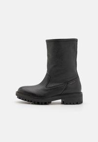 Juodas odinis kulkšninis botas su tekstūruotu paviršiumi, apvalia nosimi ir masyvi gumaus pagrindo, turinčioje horizontalių griovelių. Prekinis ženklas šone.