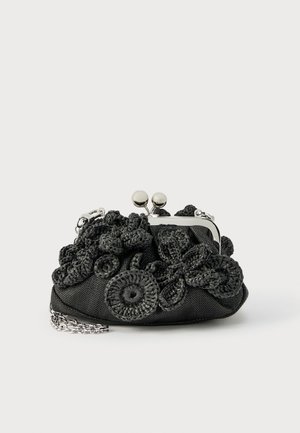 Small black fabric purse with silver clasp and chain, adorned with textured black crocheted floral and circular decorations.