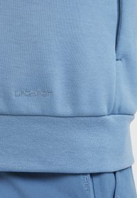Tissu de sport bleu clair avec le logo "DRI-FIT" brodé au-dessus de la ceinture côtelée et pantalon bleu clair assorti en dessous.