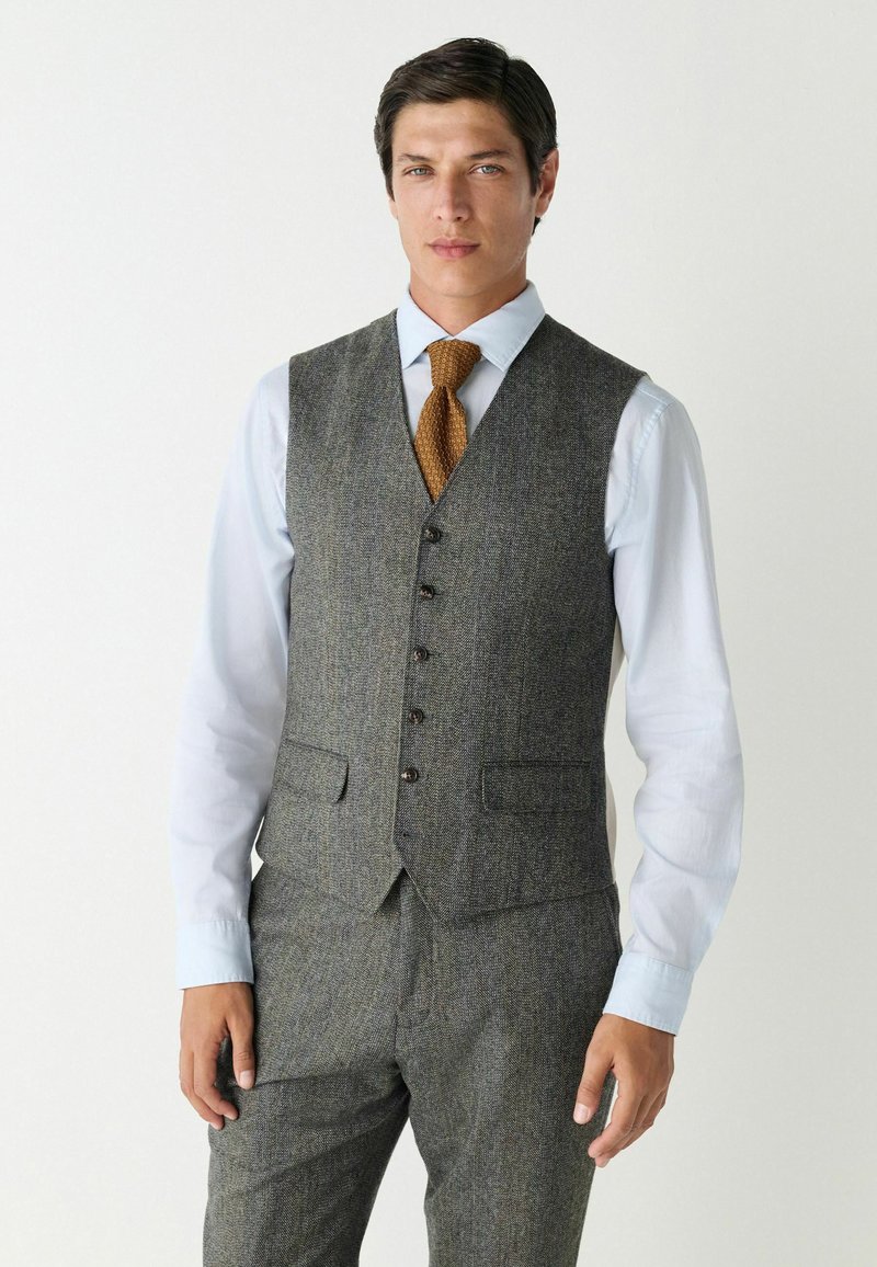 Gray tweed vest with a tailored fit, featuring a five-button front, two front pockets, and a smooth, light blue dress shirt underneath.