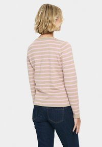 Randig långärmad tröja i ljus beige med rosa ränder. Mjuk material och standardpassform, kombinerad med mörkblå jeans.