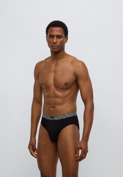 Μαύρο εσώρουχο με γκρι ζώνη μέσης που φέρει το λογότυπο Armani. Το ύφασμα φαίνεται λείο και εφαρμοστό, σχεδιασμένο για άνεση.