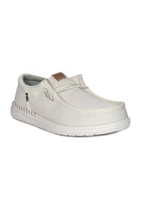 Scarpe slip-on bianche in tessuto con tomaia testurizzata, suola in gomma e cuciture decorative. Presentano una piccola etichetta con logo marrone sulla linguetta.