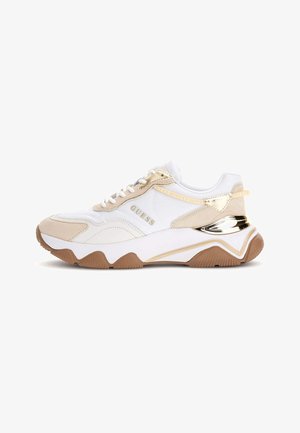 Baskets blanches avec des accents beige, présentant une tige texturée et un détail doré brillant sur le talon. Semelle en caoutchouc avec un motif en zigzag.