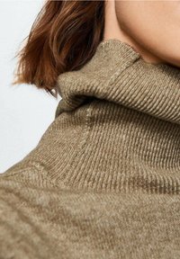 Jersey de punto marrón con cuello alto y un patrón de canalé texturizado. La tela es suave, con un ajuste holgado alrededor del cuello y los hombros.