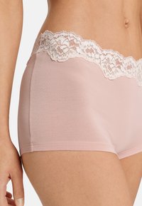 Růžové klučičí boxerky s krajkovým pasem v květinovém vzoru. Tkanina vypadá hladce a pružně, s bezešvou konstrukcí pro pohodlí.