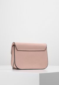 Borsa a tracolla in pelle rosa con patta pieghevole, tracolla a catena argentata e cuciture nere a contrasto lungo i bordi. Texture liscia, forma compatta.
