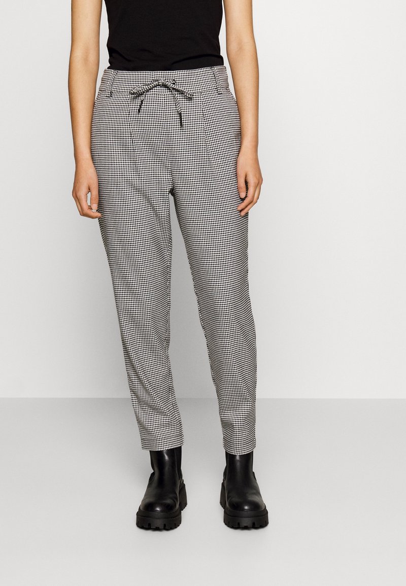 Svartvitt rutiga byxor med dragsko i midjan, avsmalnande ben och sidofickor, ihop med svarta ankelstövlar.