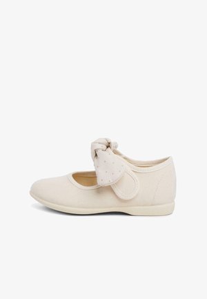 Ballerines en tissu beige clair avec un bout rond. Présentent un détail en nœud à l'arrière et une tige douce et texturée. Semelle flexible.